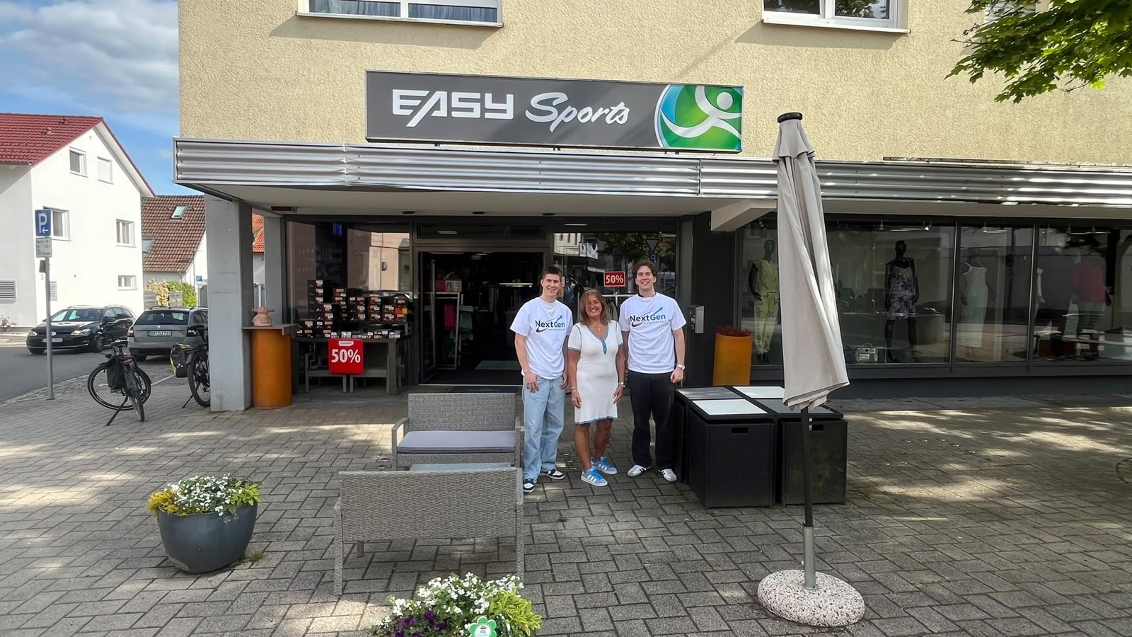 Tim Sziller und Tim Eisenhardt von NextGen Management mit der Inhaberin vor dem Ladengeschäft von Easy Sports in Holzgerlingen